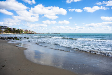 Peaceful beach scene with gentle waves, soft clouds, and a clear horizon.
