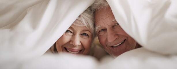 The Senior Couple Snuggling Under White Comforter in Bright Cozy Bedroom Morning