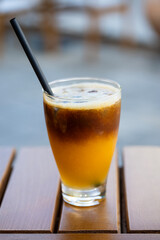 Layered iced coffee with citrus tones served in a clear glass on a wooden surface.