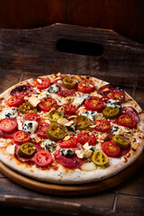Pizza with salami, jalapeno pepper, cherry tomatoes and mozzarella cheese. Soft focus.	