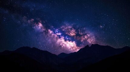 Majestic night sky displays vibrant colors of the Milky Way over dark mountain silhouettes during a clear evening