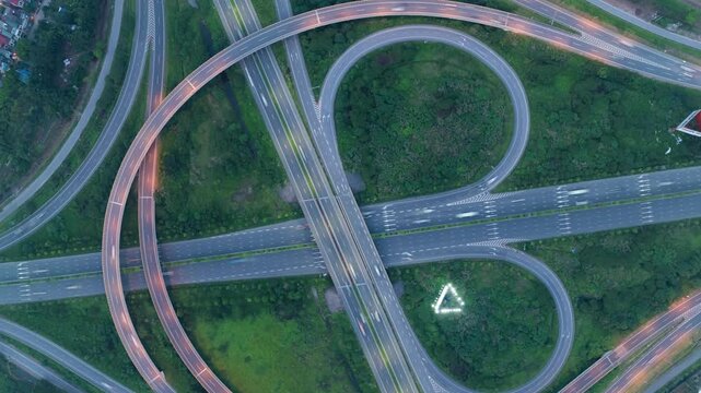 An overhead hyperlapse drone shot of a complex cloverleaf interchange in Hanoi, Vietnam, with cars and trucks navigating the ramps.