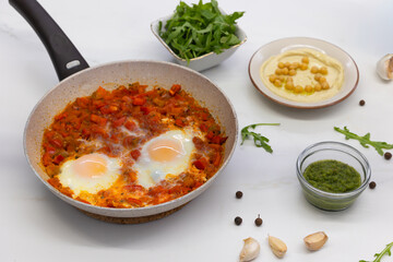 Homemade Shakshuka with poached eggs and fresh side ingredients