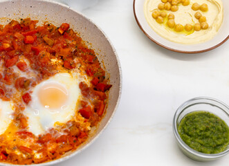 Homemade Shakshuka with poached eggs and fresh side ingredients