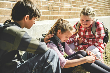 sad moment Elementary Age Bullying in Schoolyard. Childs consoling girl