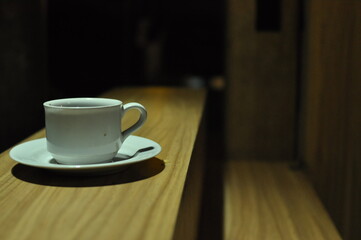 White coffee cup on wooden table in low light, creating a warm and cozy atmosphere, perfect for cafe, beverage, relaxation, and lifestyle concepts.