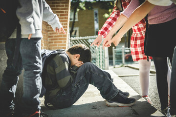 sad moment Elementary Age Bullying in Schoolyard. boy bully by a group of four friends