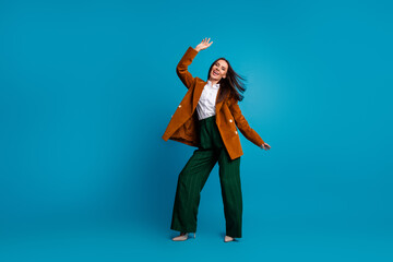 Confident young businesswoman in stylish formalwear posing joyfully against a vibrant blue background for fashion advertising