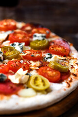 Pizza with salami, jalapeno pepper, cherry tomatoes and mozzarella cheese. Soft focus.	
