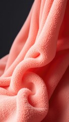 Soft Salmon Hued Fabric Folds and Drapes Elegantly, Creating a Warm, Plush Texture with Subtle Curves and Highlights on a Dark Backdrop