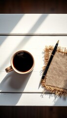 Morning motivation with black coffee, a pen and rustic burlap on a white wooden surface under bright sunlight