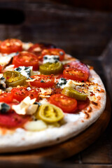 Pizza with salami, jalapeno pepper, cherry tomatoes and mozzarella cheese. Soft focus.	