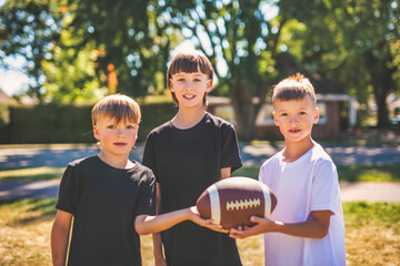 brother playing American football. Kids play football in sunny summer park.