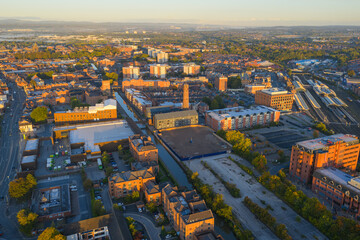 Obraz premium Sunlit aerial view of Chester Railway Station with canal, warehouses, and historic chimney.