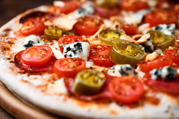 Pizza with salami, jalapeno pepper, cherry tomatoes and mozzarella cheese. Soft focus.	