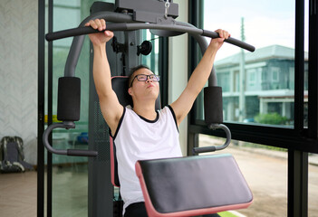 A man with down syndrome exercising on a weight machine at the gym
