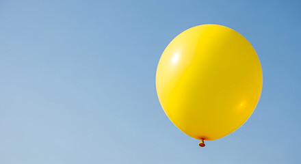 A vibrant yellow balloon floats against a clear, bright, and cloudless blue sky.