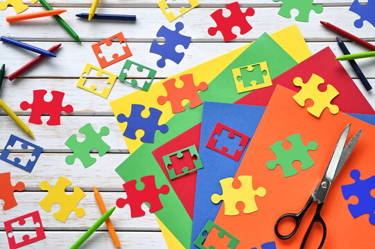 Colorful paper jigsaw puzzle pieces with crayons - concept autism or teamwork  - Powered by Adobe