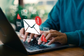 Person typing on laptop while receiving urgent email notifications in a bright indoor setting during the day