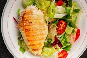 Grilled chicken breast salad chicken breast tomato, green leaf lettuce, salad mix snack vegetables snack gourmet food background on the table rusticcopy space keto and paleo diet vegan and vegan food