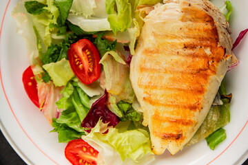 Grilled chicken breast salad chicken breast tomato, green leaf lettuce, salad mix snack vegetables snack gourmet food background on the table rusticcopy space keto and paleo diet vegan and vegan food