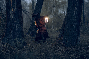 Obraz premium Eerie plague doctor illuminates a dark, mysterious forest with lantern light.