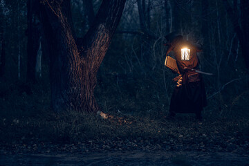 Mysterious figure illuminated by lantern studies ancient tome within shadowy forest.