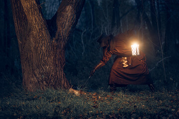 Mysterious figure illuminated by lantern wanders through a dark, autumnal forest.