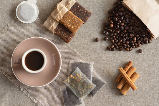 Cup of coffee, protein bars, roasted coffee beans and cinnamon sticks on a table