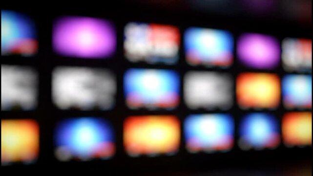 A blurry, abstract view of a grid of colorful, glowing video thumbnails on a digital screen.