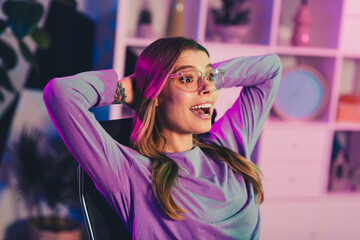 Expression of excitement and creativity, young female blogger enjoying neon-lit workspace setting