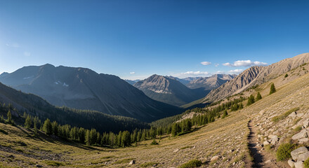 A scenic mountain landscape with a hiking trail and clear blue sky on a sunny day in the wilderness