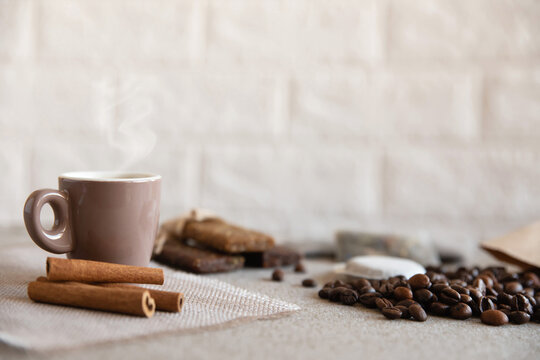 Cup of coffee, protein bars, roasted coffee beans and cinnamon sticks on a table