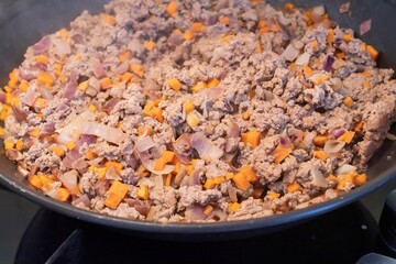 Ground beef with carrots and onions cooking in a pan. Steamy hot dish in the kitchen showing homemade meal preparation, fresh ingredients, and simple comfort food recipe on stove.