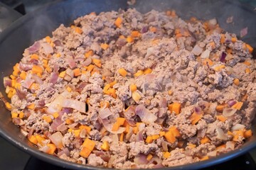 Ground beef with carrots and onions cooking in a pan. Steamy hot dish in the kitchen showing homemade meal preparation, fresh ingredients, and simple comfort food recipe on stove.