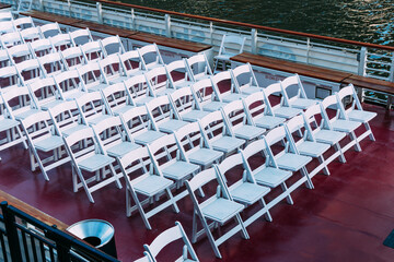 Rows of white chairs arranged on a boat deck, ready for an event.
