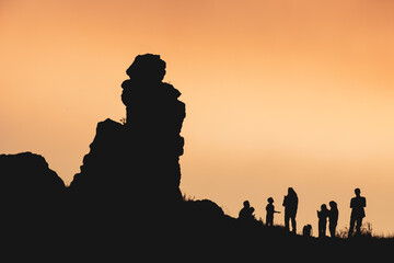 A group of people are silhouetted against a sunset