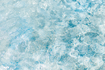 Clear and calm water glistens under sunlight, creating gentle ripples across a tranquil surface, conveying a sense of peace and relaxation