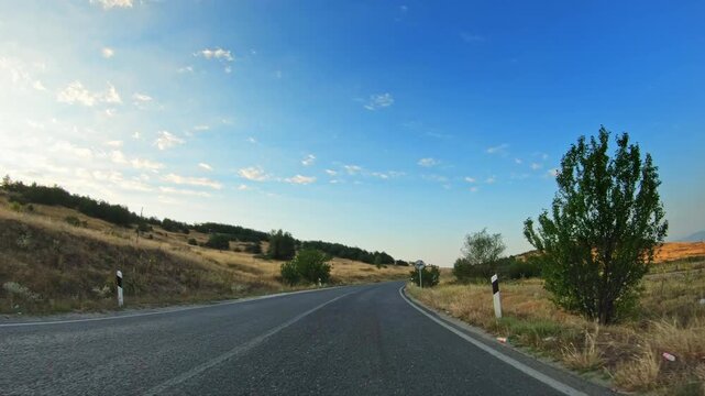 POV car diving on local asphalt road, countryside scenery, sunny summer day