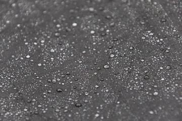 Gros plan minimaliste sur un parapluie noir avec gouttes de pluie, texture épurée
