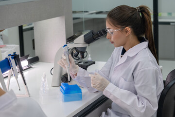 Scientist working in a laboratory examining samples under a microscope