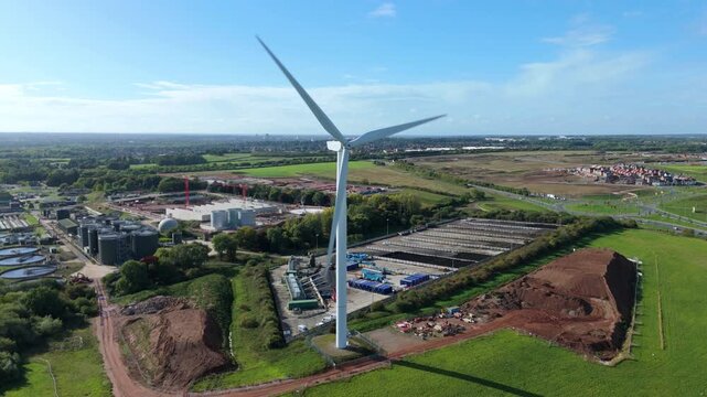 Aerial drone view of large wind turbine and wastewater sewage treatment plant, renewable energy generation and clean drinking water and sanitation, storage silos and settling pools, Leicester England