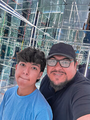 Portrait of a father and his son inside a mirror room with infinite reflections.