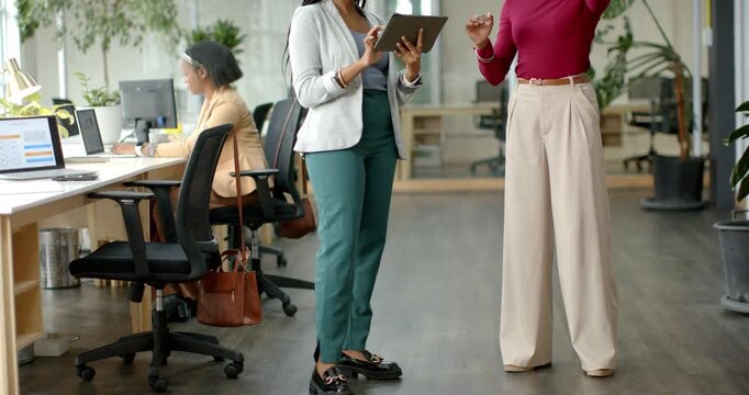 Tapping tablet, African American women in office guiding headset user through interface testing - Powered by Adobe