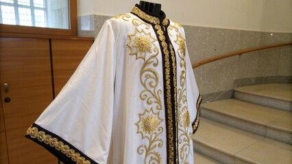 Elegant White and Gold Traditional Robe with Black Trim Details for Cultural Fashion Concept