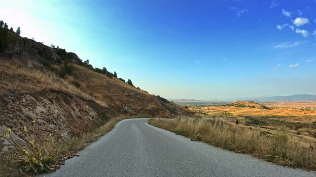 Mountain nature, dry vegetation, POV car drive on curvy narrow road