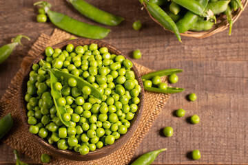 Fresh green peas and pods in a bowl on wooden table. Vegetable healthy food.  