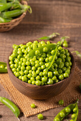 Fresh green peas and pods in a bowl on wooden table. Vegetable healthy food.  