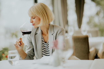 Woman enjoys a glass of red wine while sitting at a restaurant table during a relaxed afternoon