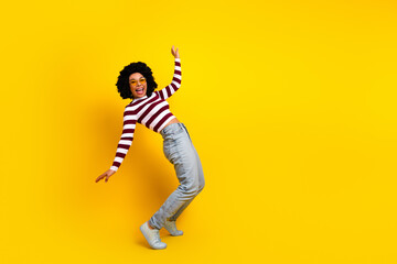 Fototapeta premium Joyful young woman in trendy casual attire posing playfully in front of a vibrant yellow background